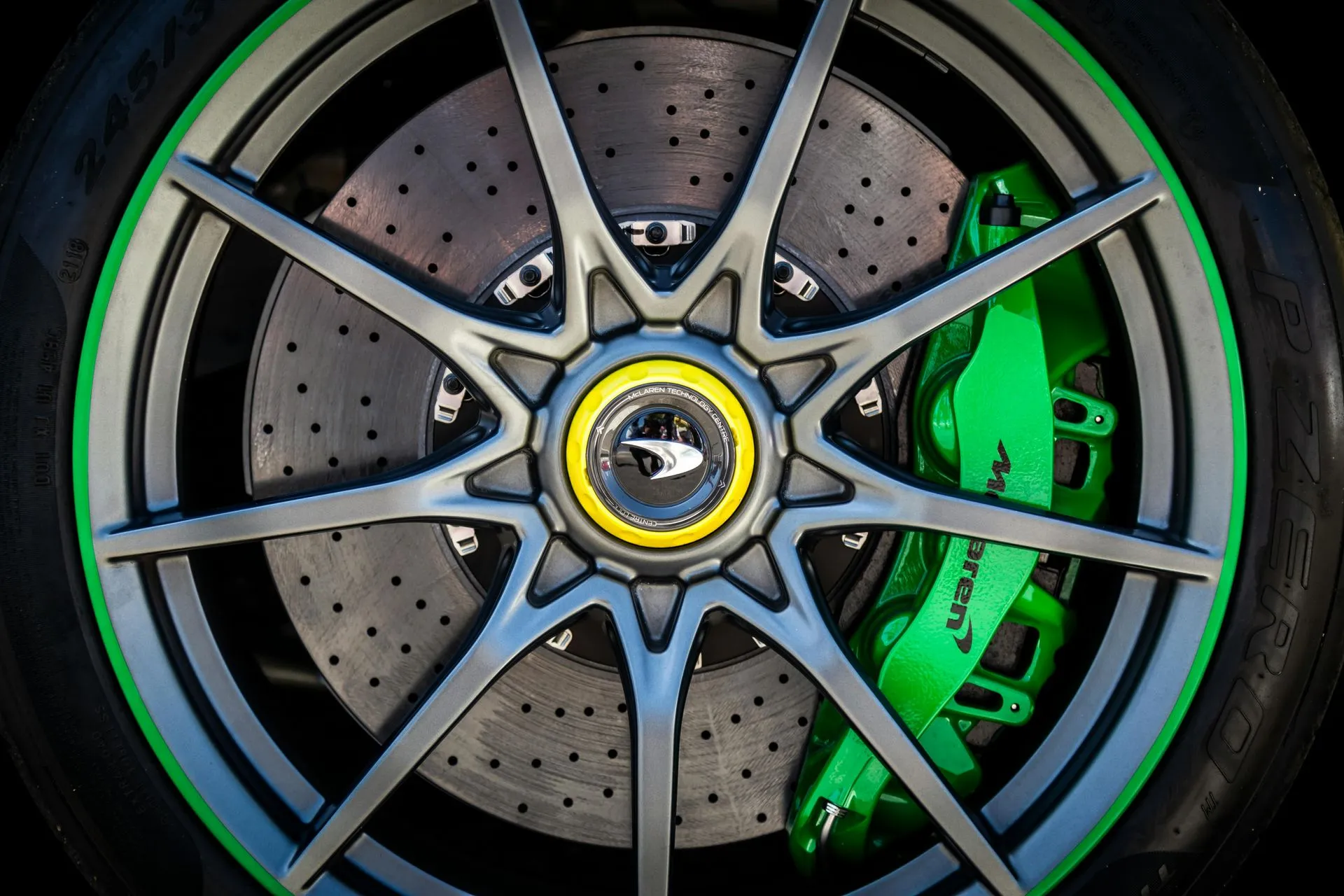 Performance car wheel with a drilled brake rotor and green brake caliper