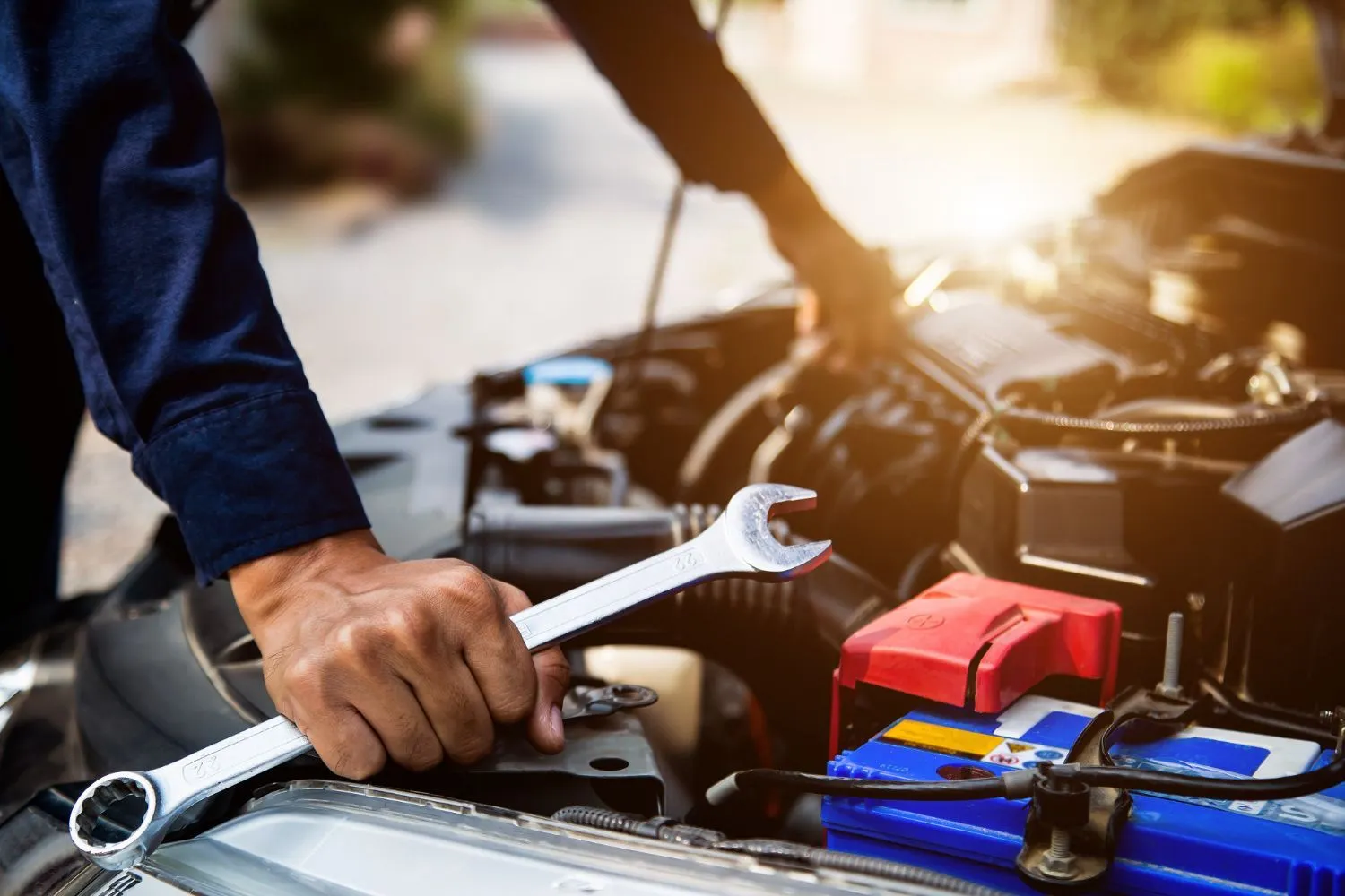 Mechanic using a wrench on a car engine next to the battery